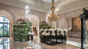 Un lobby lujoso con una gran araña, pisos de mármol y decoraciones ornamentales.