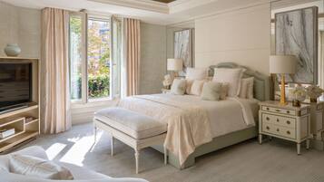 A bedroom with a large bed, bedside tables, a bench, a TV, and a window with curtains.