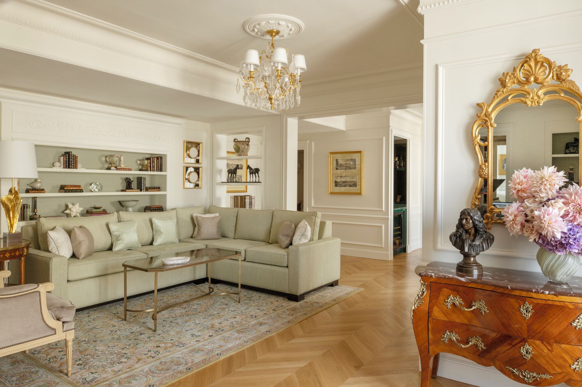 A spacious living room with a light-colored sofa, a coffee table, and a decorative mirror.