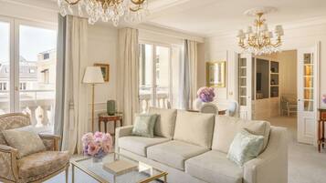 A spacious living room with a beige sofa, a glass coffee table, and a chandelier.