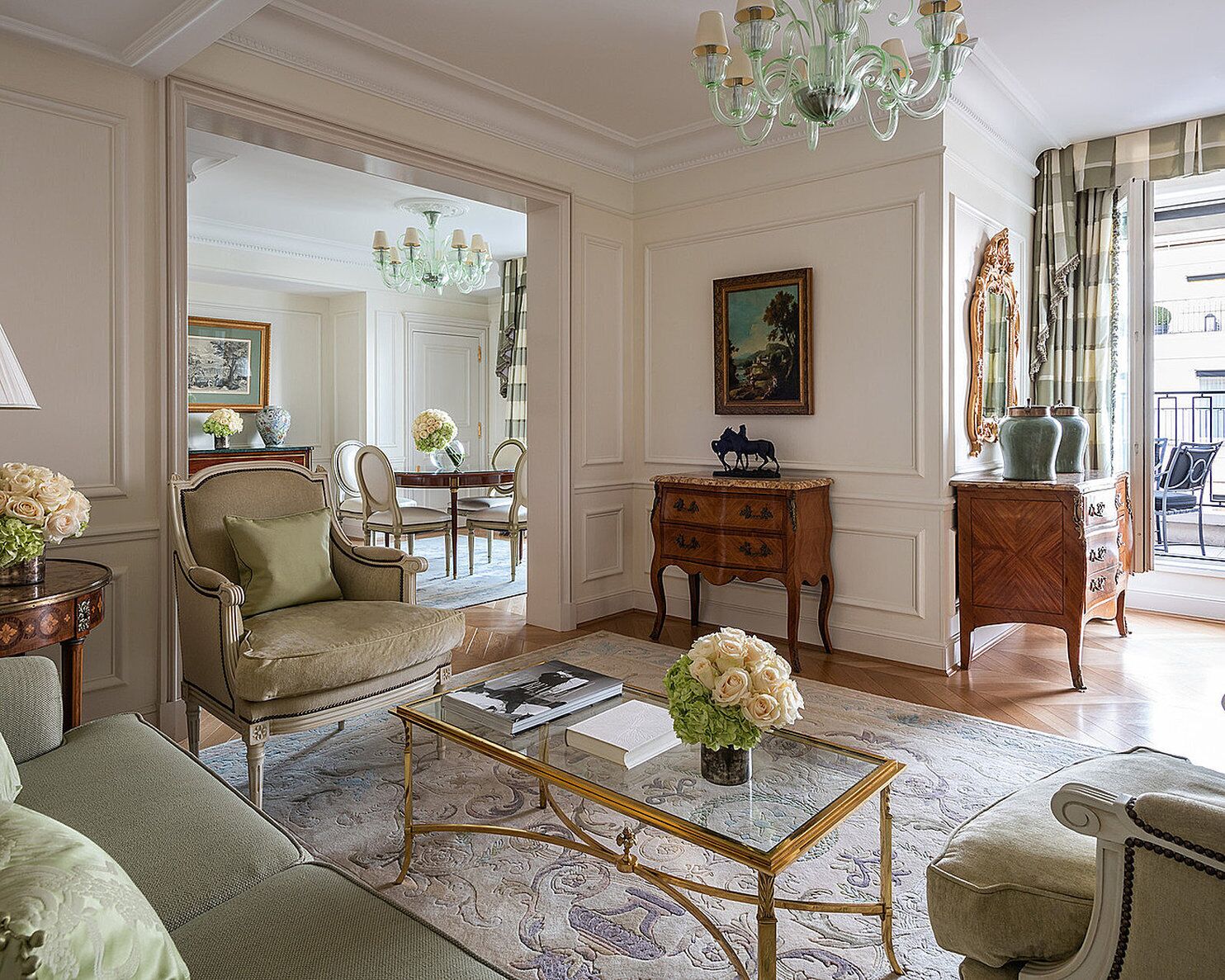 Uma sala de estar bem decorada com sofá, poltrona, mesa de centro e um espaço de jantar com mesa e cadeiras.