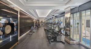 A modern gym with exercise equipment, a bench, and a wall with towels.