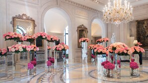 Un vaste hall d’entrée agrémenté de lustres somptueux, d’un sol en marbre et de compositions florales présentées dans de simples vases en verre.