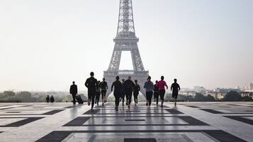 Un grupo de personas trotando en una plaza empaveda con la Torre Eiffel al fondo.