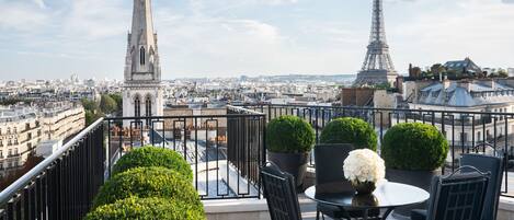 Una terraza en la azotea con vistas a la Torre Eiffel, una aguja de iglesia y un paisaje urbano.
