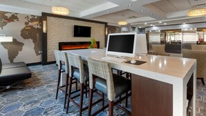 A modern hotel lobby with a stone-patterned floor, a reception desk, a flat-screen TV, and comfortable seating areas. - Best Western Plus Toronto Airport Hotel (Mississauga)