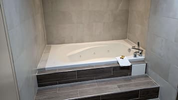 Une salle de bain moderne avec une baignoire sur pieds, des marches en bois foncé et une zone de douche carrelée.