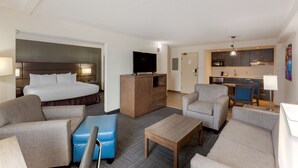 A hotel room with a bed, sofa, armchair, and a small table. There is a kitchenette in the background. - Best Western Plus Toronto Airport Hotel (Mississauga)