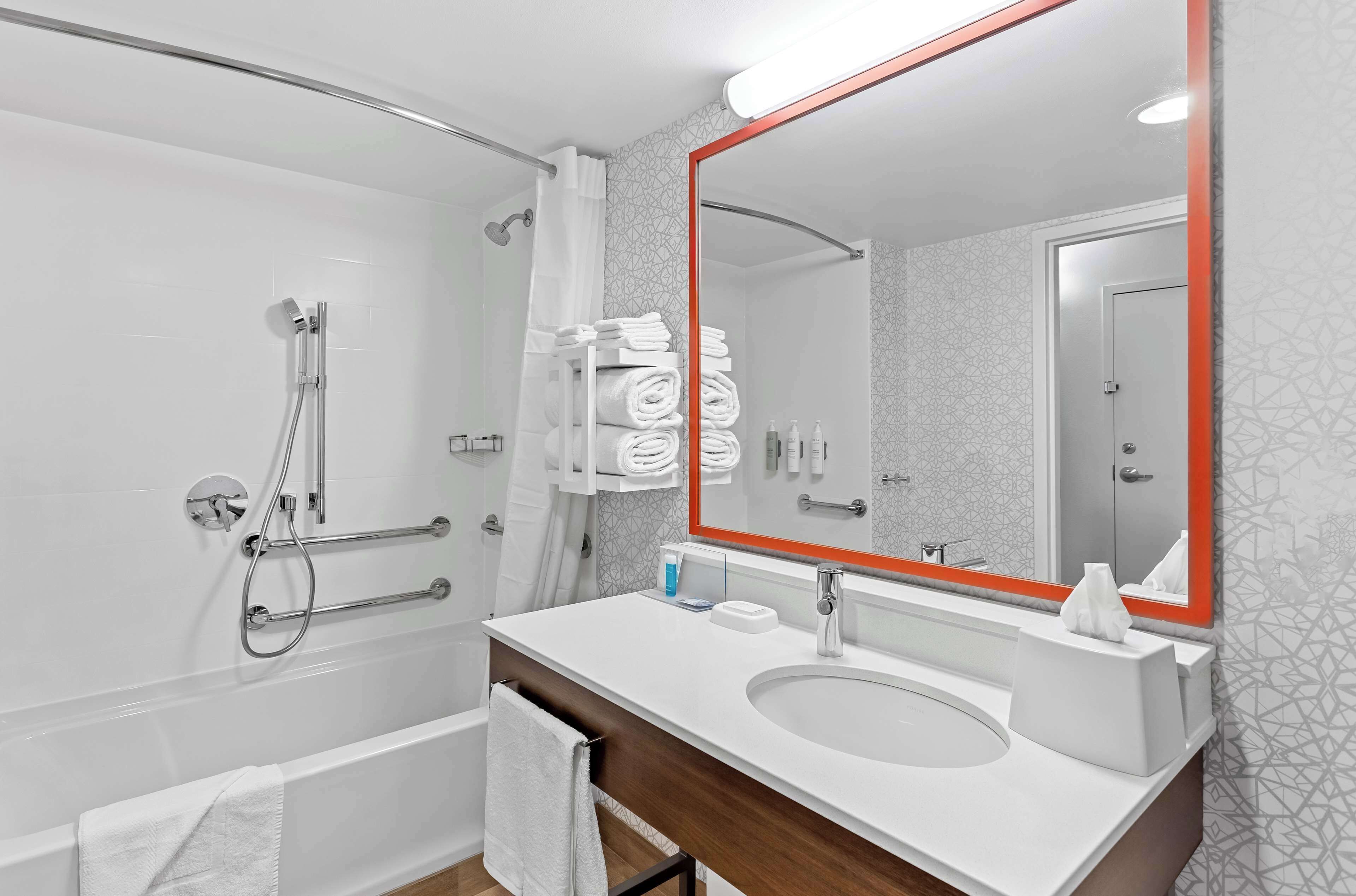A modern bathroom with a white sink, mirror, and shower.