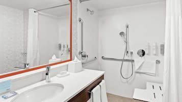 Un baño moderno con un lavamanos grande, un espejo de marco rojo, una ducha con cabezal de ducha manual y un perchero para toallas.