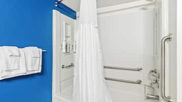 Un baño con pared azul, cortina de ducha blanca y barras de apoyo.