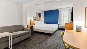 Une chambre d’hôtel avec un lit, un canapé, un bureau et une chaise.