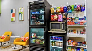 Un espace où l’on peut acheter des collations, avec un four à micro-ondes et des sièges dotés de chaises jaunes.