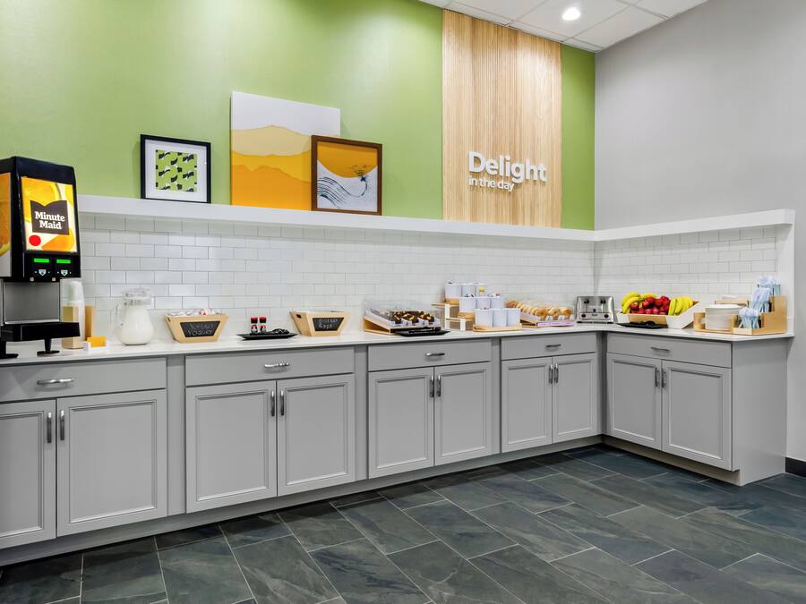 A modern kitchen with a coffee machine, tea station, and various food items on the counter.
