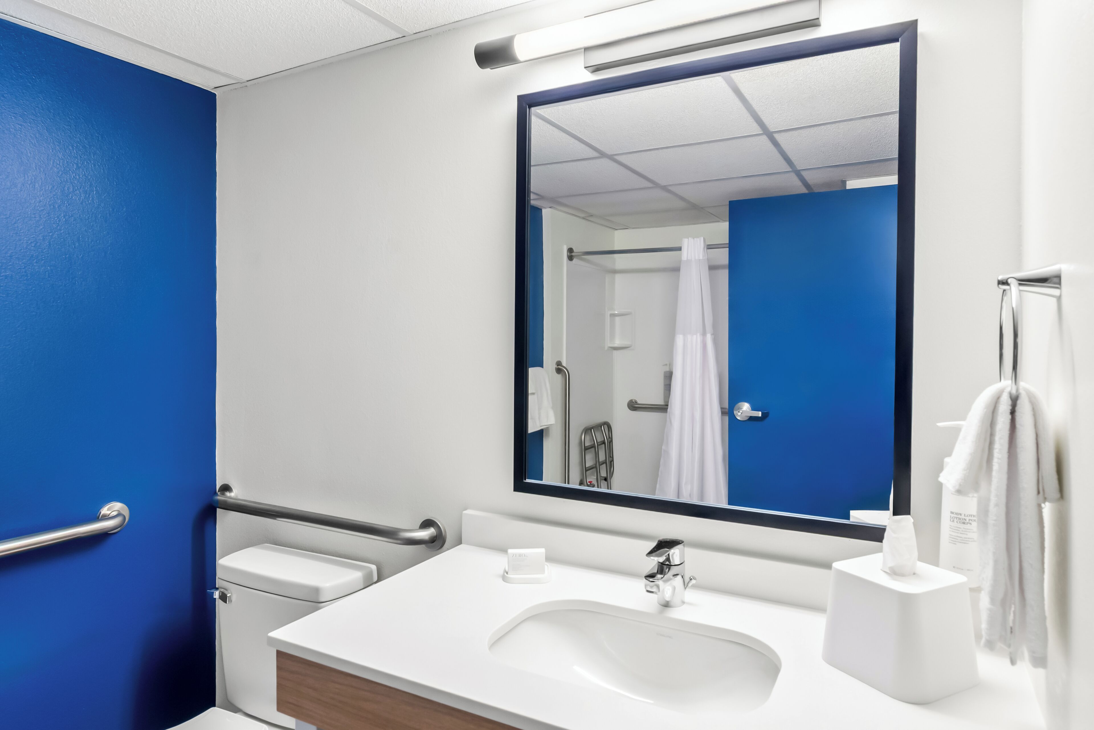 A bathroom with a white sink, a mirror, and a blue wall.