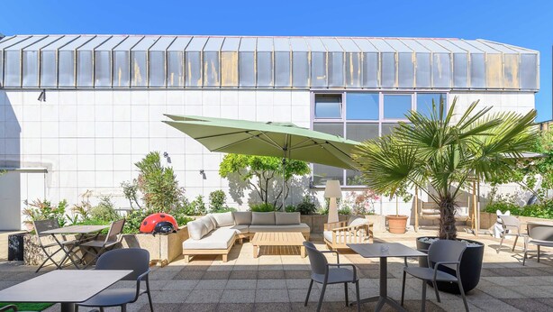 An outdoor patio with seating, a table, and a large umbrella.
