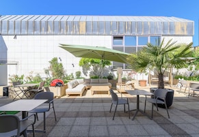 An outdoor patio with seating, a table, and a large umbrella.