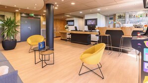 A modern lobby with a reception desk, seating area, and a bar.