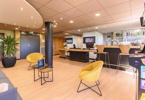 A modern lobby with a reception desk, seating area, and a bar.