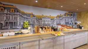 A breakfast buffet with a variety of food items and a mural of a grand building in the background.