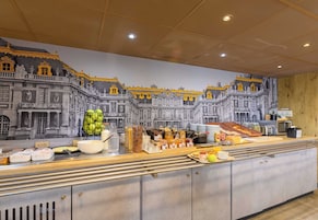 A breakfast buffet with a variety of food items and a mural of a grand building in the background.