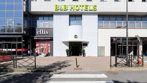A B&B hotel with a modern facade, a restaurant named 'Ellis Gourmet Burger' on the ground floor, and a clear entrance.