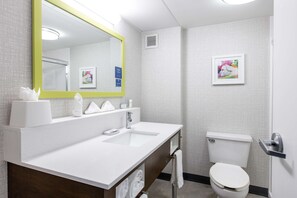 A modern bathroom with a white sink, a mirror with a yellow frame, a toilet, and a towel rack.