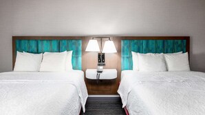 A hotel room with two beds, a wooden headboard, a built-in phone, and teal patterned curtains. - Hampton Inn Columbus/Dublin (Dublin)