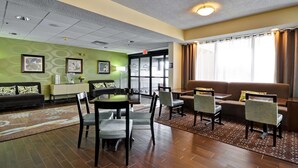 A hotel room with a dining area, a sofa, and a window with curtains. - Hampton Inn Columbus/Dublin (Dublin)