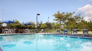 A swimming pool with lounge chairs and umbrellas, surrounded by a fence and trees. - Hampton Inn Columbus/Dublin (Dublin)