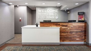 A reception desk with a "WELCOME TO THE BUCK EYE STATE" sign, a wooden accent wall, and a Hilton Honors display. - Hampton Inn Columbus/Dublin (Dublin)