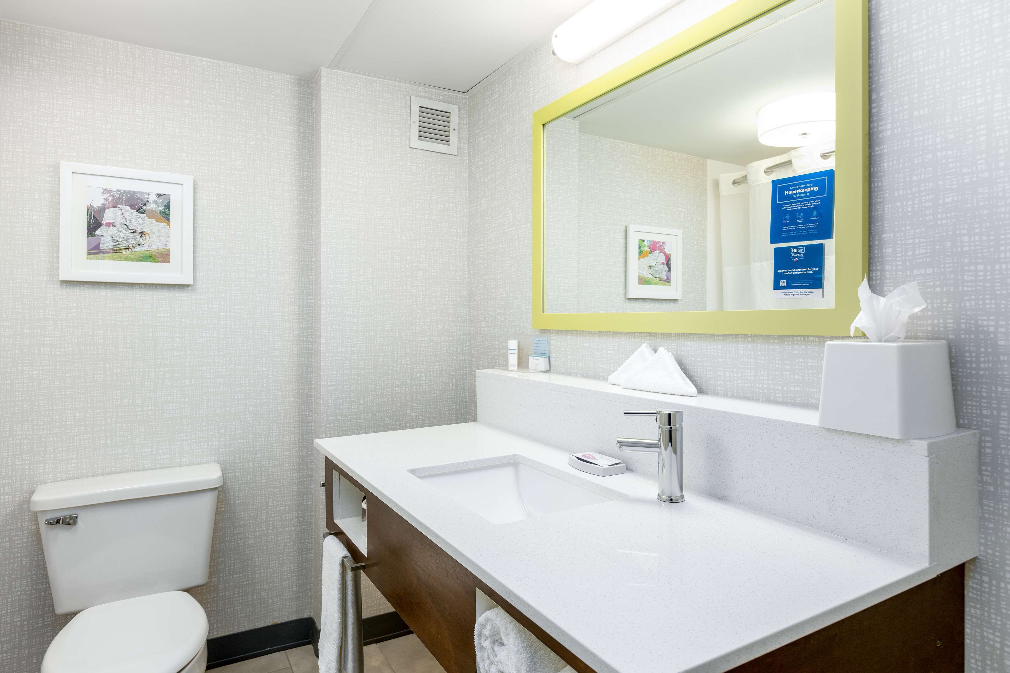A bathroom with a white toilet, a sink with a mirror, and a towel rack.