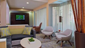 A modern living room with a sofa, two armchairs, a coffee table, and a television. - Courtyard by Marriott Orlando International Dr / Conv Cntr (Orlando)