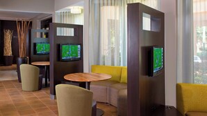A modern lounge area with seating, a television, and a view of the outdoors. - Courtyard by Marriott Orlando International Dr / Conv Cntr (Orlando)