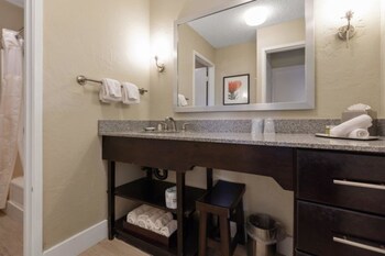 A bathroom counter with a towel, a tissue box, and three bottles of Terra Pure products. at Plantation Hale Suites