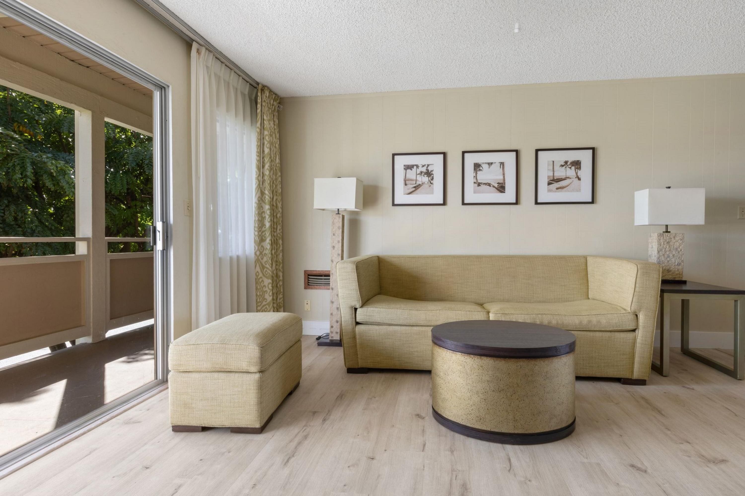 A modern living room with a sofa, ottoman, round coffee table, and two wall-mounted lamps.