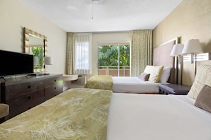 A hotel room with two beds, a television, a desk, and a window with curtains.