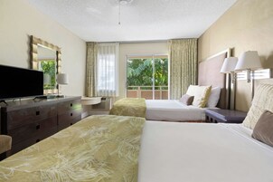 Habitación de hotel con dos camas, televisor, escritorio y ventana con cortinas.