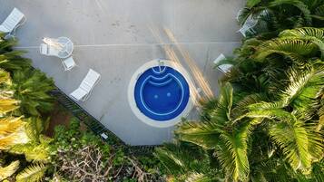 A circular pool with a blue center, surrounded by white lounge chairs and a metal fence.
