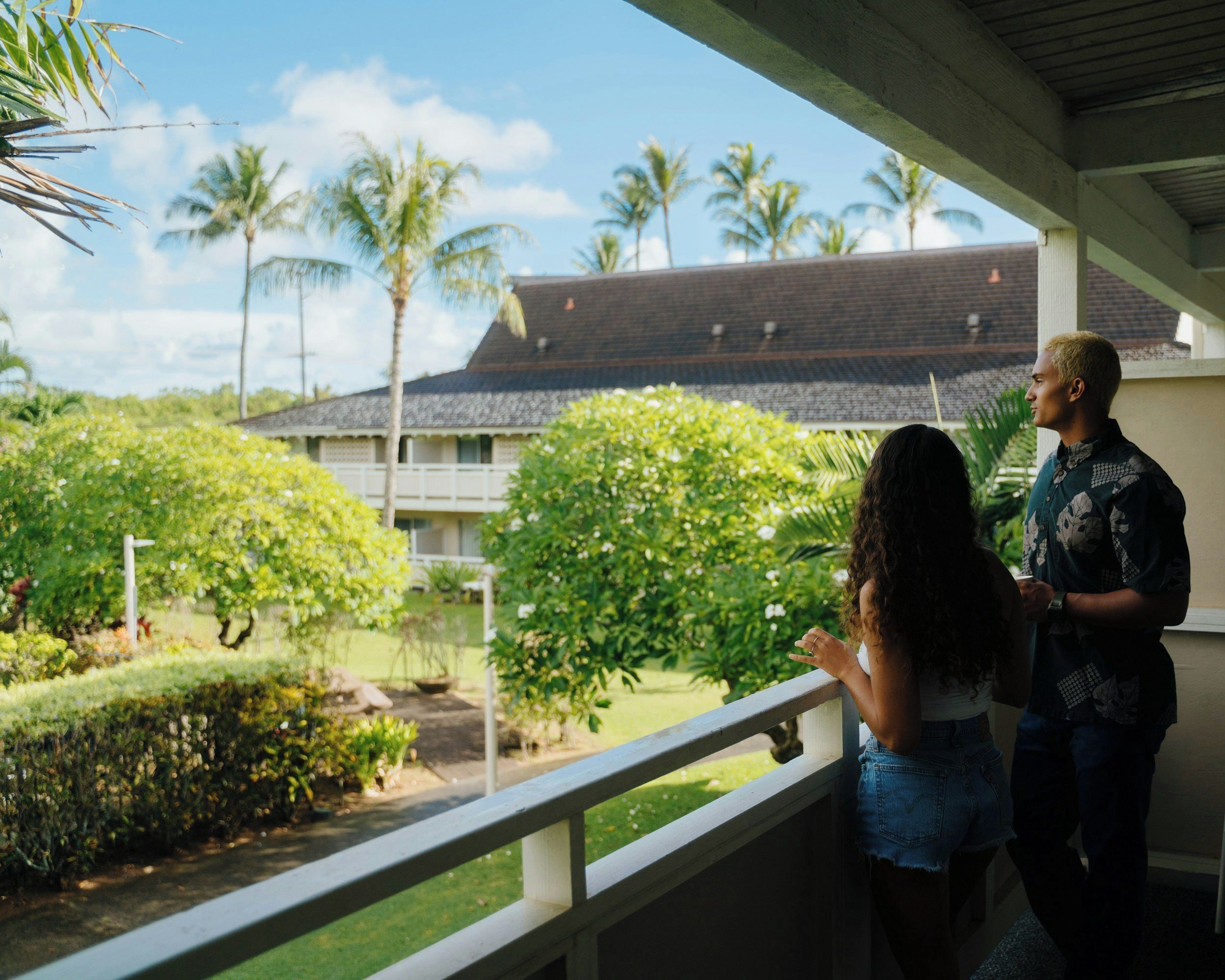 A balcony with a view of a building and palm trees.