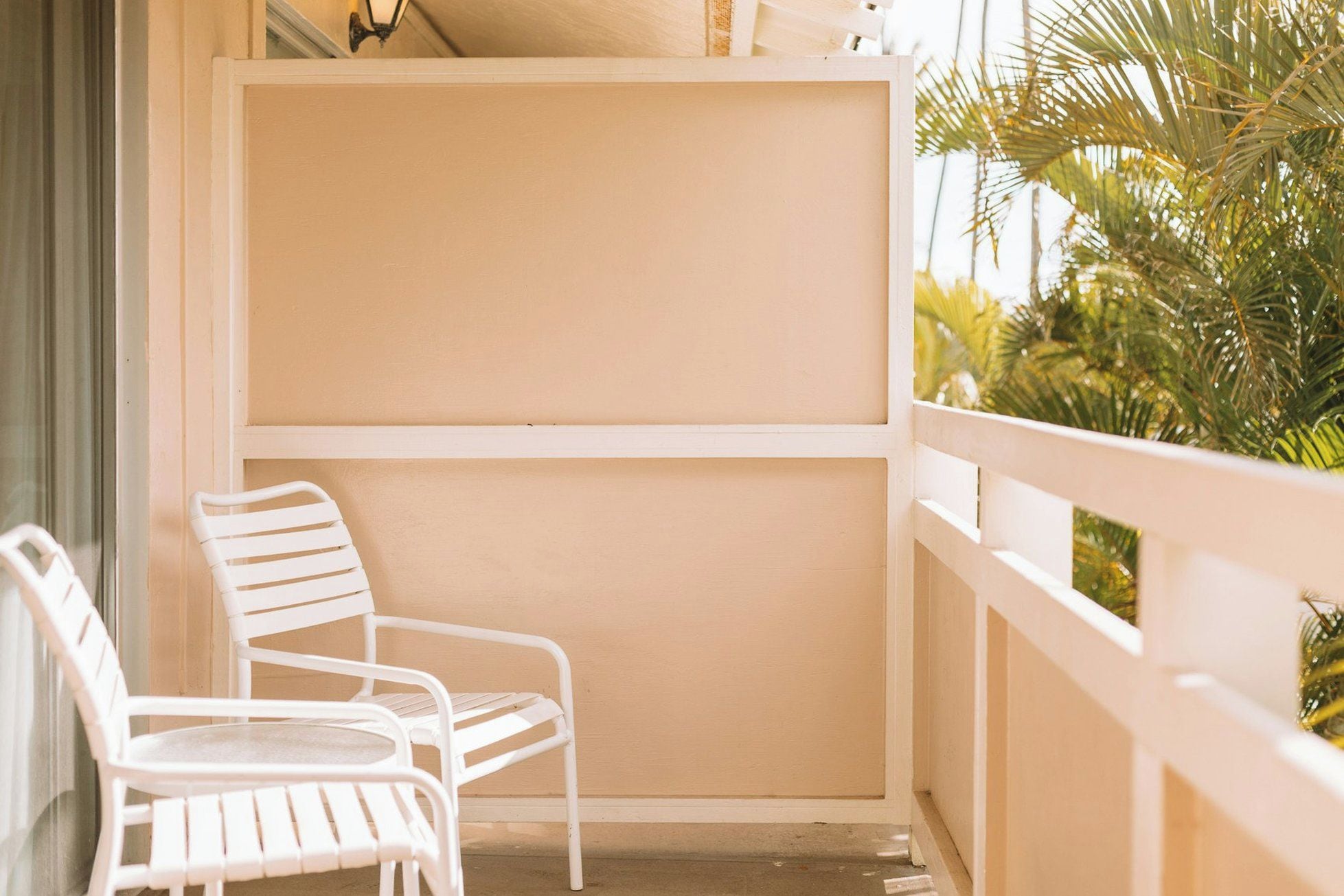 A balcony with white railings and two white chairs.