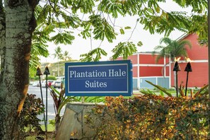 Señal de Plantation Hale Suites con vista a un edificio y árboles al fondo.