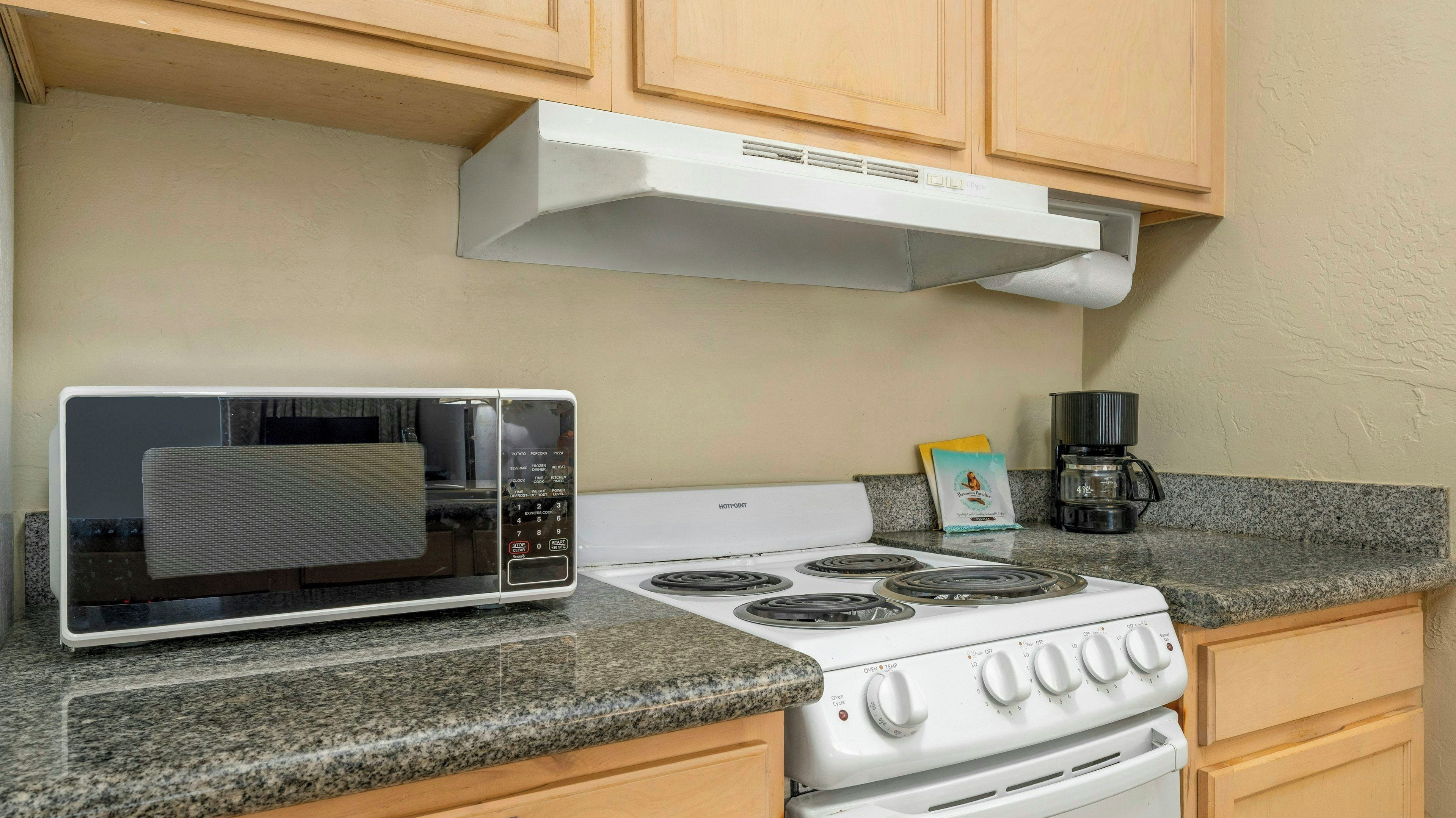 Una cocina equipada con microondas, estufa y cafetera.