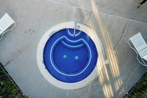 Una piscina circular con diseño de mosaico azul, rodeada por una terraza de concreto.