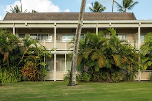 A two-story building with a flat roof and a balcony on the second floor.