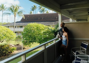 Un balcon donnant sur un immeuble avec un toit en tuiles et des palmiers.