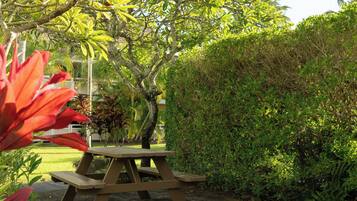 A picnic table in a garden with dense foliage and a well-maintained lawn.