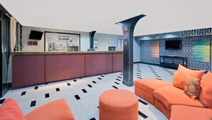 A reception area with a counter, seating area, and patterned walls. - Super 8 by Wyndham Hermitage Nashville (Hermitage)