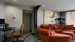 A modern living room with a sectional sofa, a dining area with a table and chairs, and a kitchen area with a microwave and cabinets. - Super 8 by Wyndham Hermitage Nashville (Hermitage)