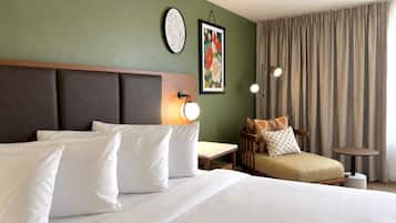 Ein Hotelzimmer mit einem großen Bett, einer kleinen Couch, einem Tisch und einem Sessel.